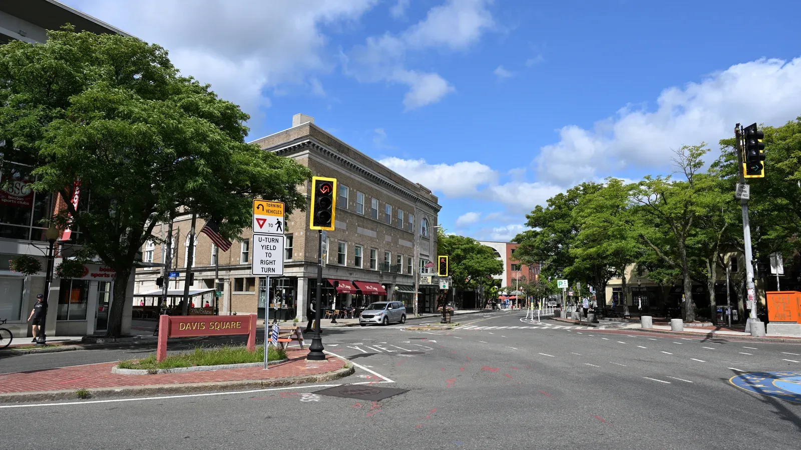 Davis Square streetscape with brick storefronts under a blue sky, Somerville, Massachusetts